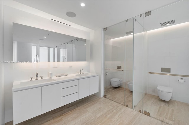 bathroom with a shower with door, vanity, tile walls, and toilet