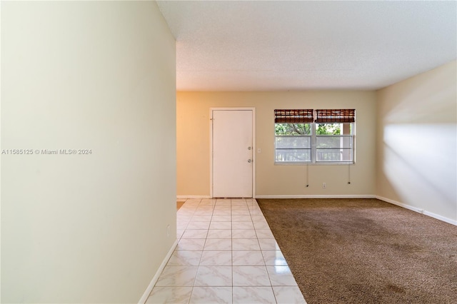 unfurnished room with light tile flooring and a textured ceiling