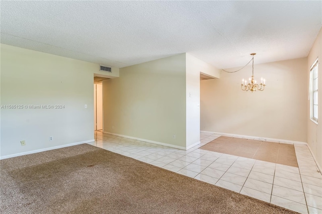 empty room with light tile flooring, a chandelier, and a textured ceiling