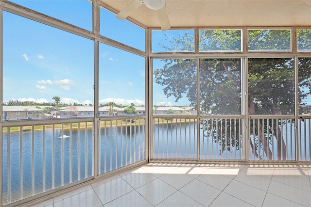 unfurnished sunroom with ceiling fan and a water view