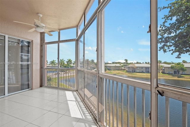 unfurnished sunroom with ceiling fan and a water view