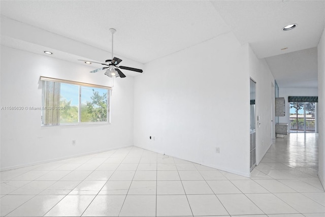 tiled empty room featuring vaulted ceiling, ceiling fan, and a wealth of natural light