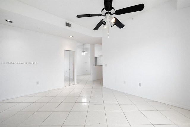 empty room with ceiling fan and light tile flooring