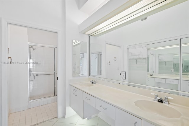 bathroom with a shower with door, dual vanity, and tile floors