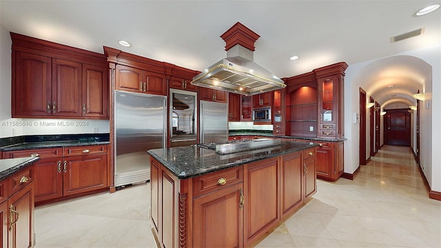 kitchen with light tile floors, a center island, built in appliances, and island range hood