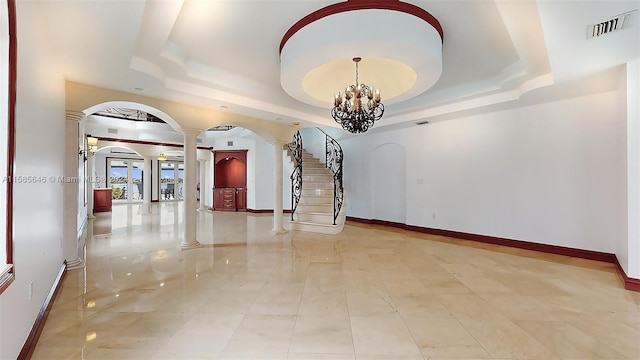 interior space with tile floors, a raised ceiling, a chandelier, and ornate columns