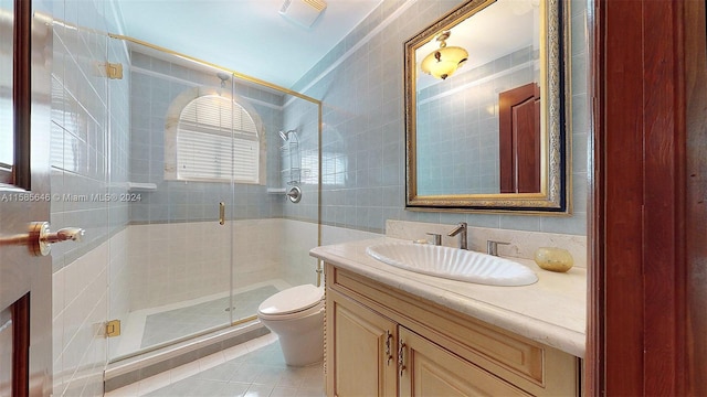 bathroom featuring toilet, tile flooring, tile walls, and vanity with extensive cabinet space