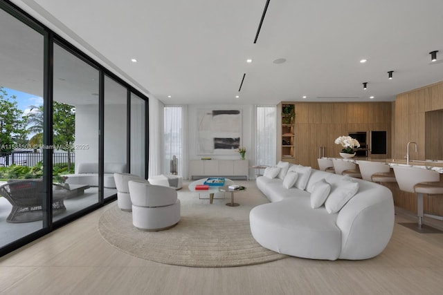 living room with sink, floor to ceiling windows, a healthy amount of sunlight, and wood walls