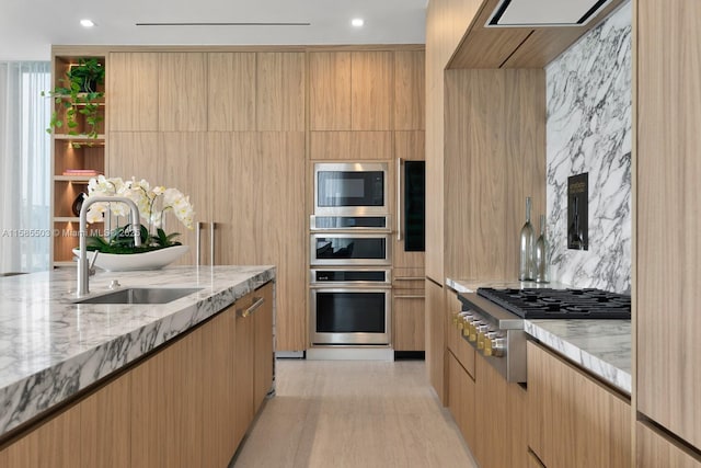 kitchen with light brown cabinetry, light stone countertops, sink, and appliances with stainless steel finishes