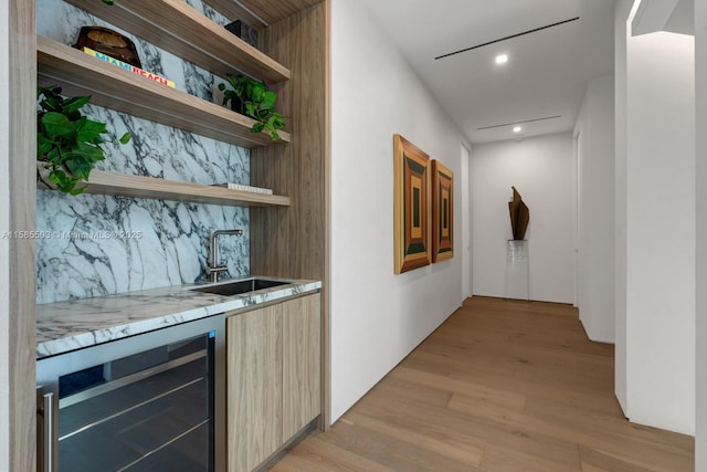 bar featuring light stone countertops, sink, wine cooler, light hardwood / wood-style flooring, and decorative backsplash