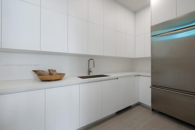 kitchen featuring white cabinets, sink, and built in refrigerator