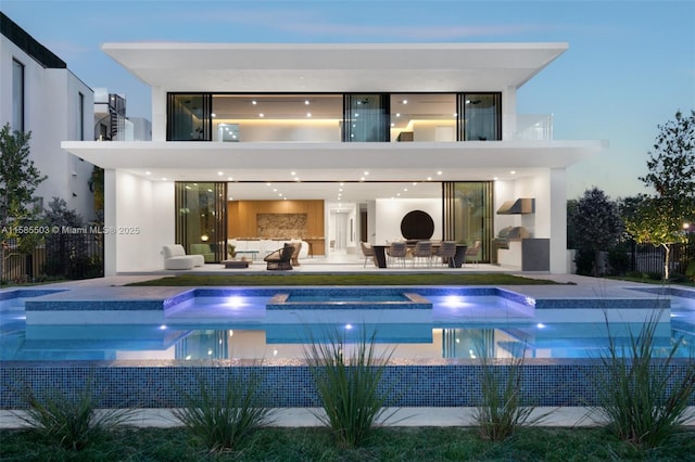 back house at dusk with outdoor lounge area, area for grilling, a balcony, and a patio area