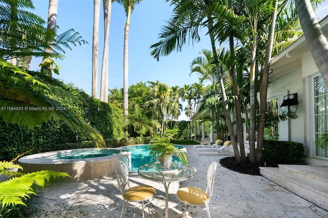 view of swimming pool featuring a patio and an in ground hot tub