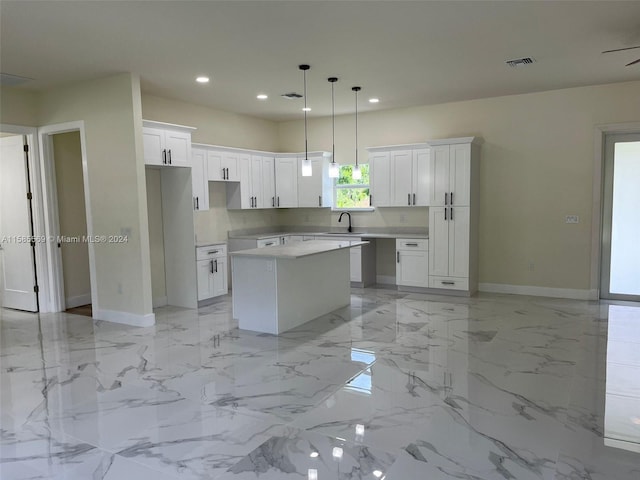 kitchen with sink, a center island, white cabinetry, and light tile floors