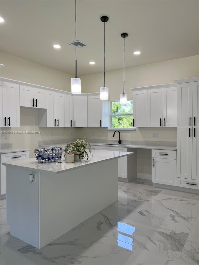 kitchen with white cabinets, sink, a kitchen island, and pendant lighting