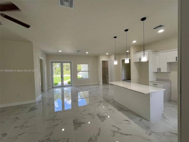 kitchen with a center island, ceiling fan, white cabinetry, and light tile flooring