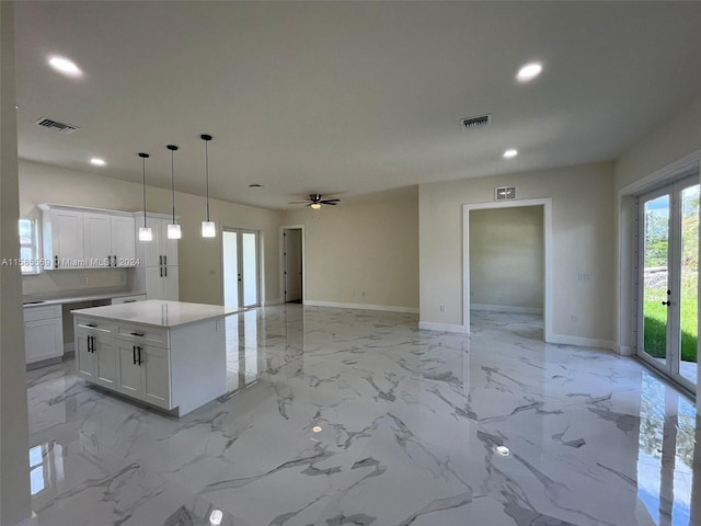 kitchen with ceiling fan, white cabinets, pendant lighting, a center island, and light tile floors