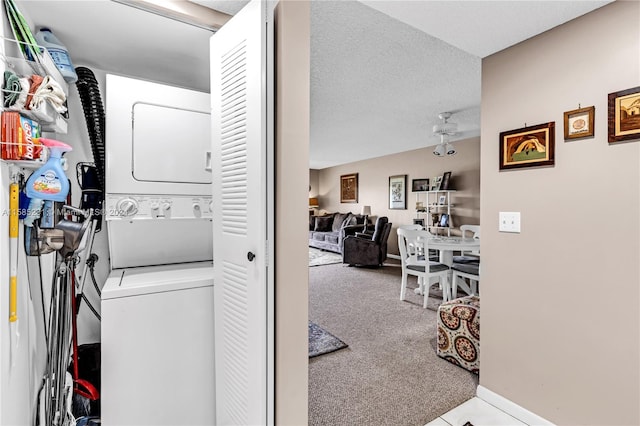 clothes washing area with stacked washer and dryer, light colored carpet, and a textured ceiling