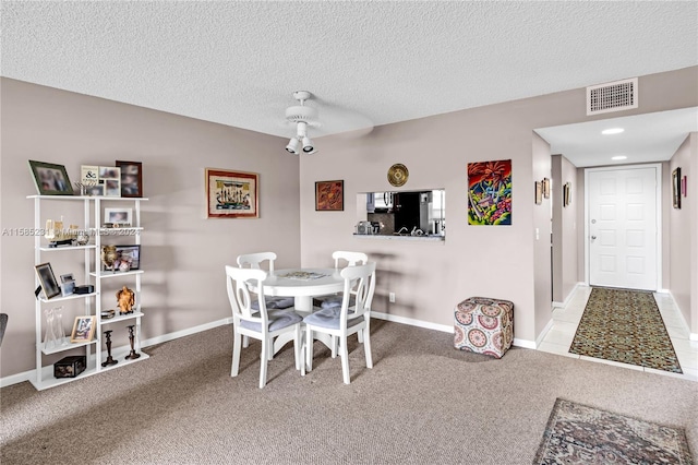 dining room featuring a textured ceiling, light colored carpet, and ceiling fan