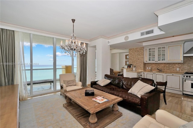 living room featuring a water view, sink, a notable chandelier, and ornamental molding