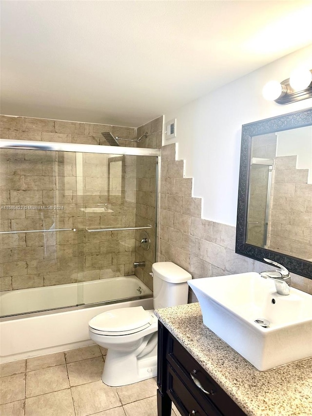 full bathroom featuring tile walls, combined bath / shower with glass door, tile floors, toilet, and vanity