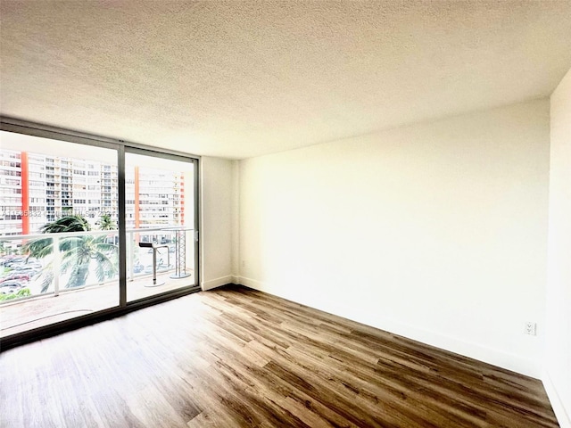 unfurnished room featuring a wall of windows, a textured ceiling, and hardwood / wood-style flooring