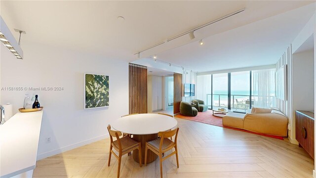 dining area with track lighting, a water view, light parquet flooring, and a wall of windows