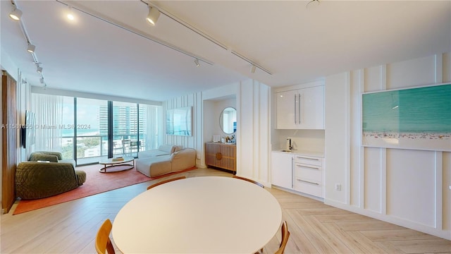 dining area with light parquet floors and track lighting