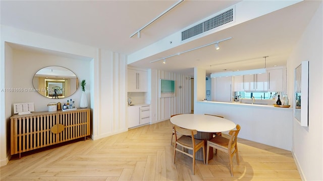 dining space featuring light parquet floors and track lighting