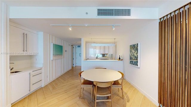 dining room with light parquet flooring, sink, and rail lighting