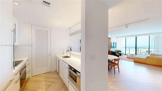 kitchen featuring black electric stovetop, a water view, floor to ceiling windows, sink, and stainless steel oven