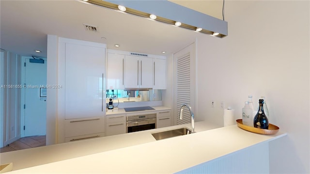 kitchen with stainless steel oven, black electric cooktop, tile floors, sink, and white cabinets