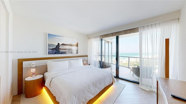 bedroom with a water view, light hardwood / wood-style floors, and access to outside