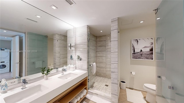 bathroom featuring tiled shower, double vanity, tile floors, washer / clothes dryer, and toilet