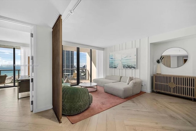 living room featuring rail lighting, a water view, and light parquet flooring