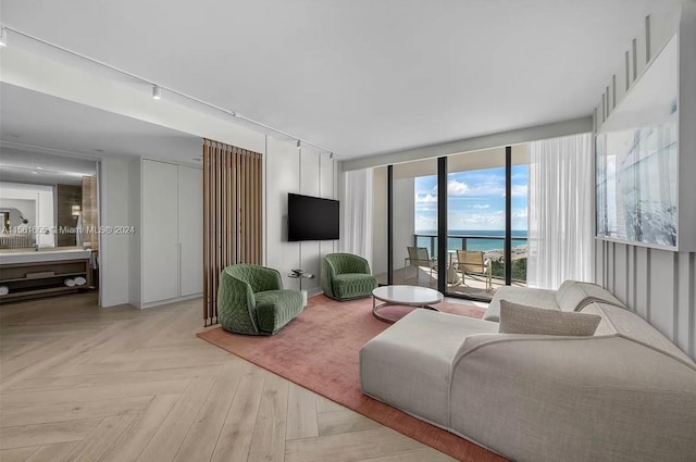 living room with track lighting, light parquet floors, expansive windows, and a water view