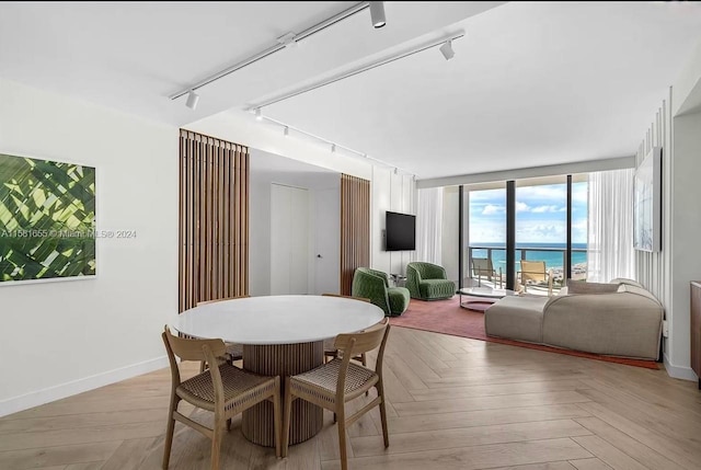 dining room featuring track lighting, a water view, and parquet flooring