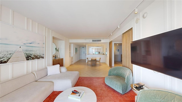 living room with rail lighting and light parquet flooring