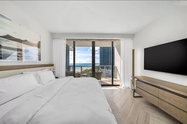 bedroom with light parquet floors, a water view, and access to exterior