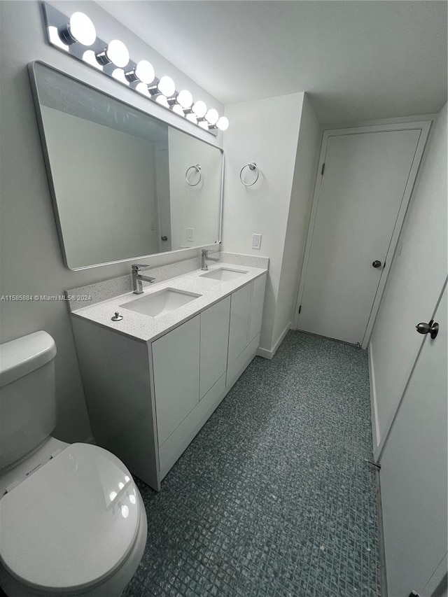 bathroom with toilet, tile floors, and double sink vanity