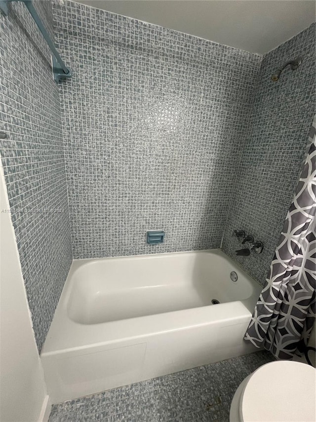 bathroom featuring toilet and shower / tub combo with curtain