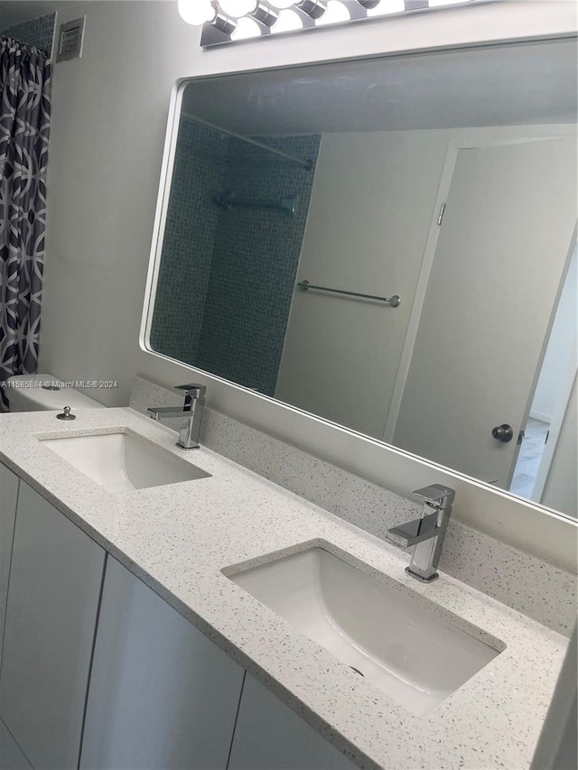 bathroom featuring double vanity and toilet