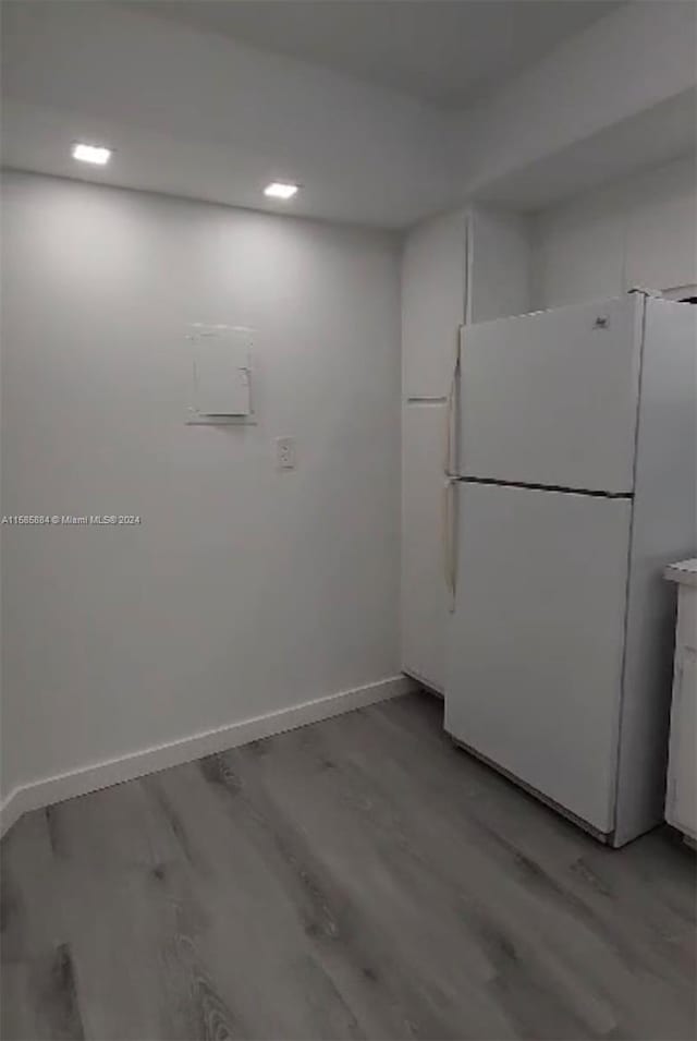 kitchen with white fridge, hardwood / wood-style flooring, and white cabinetry