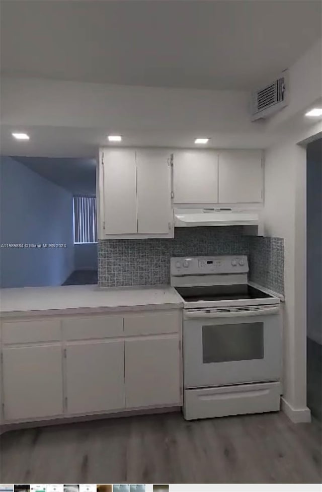 kitchen with white cabinets, wood-type flooring, tasteful backsplash, and electric stove