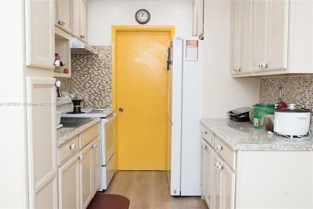 kitchen with backsplash, white appliances, and light wood-type flooring