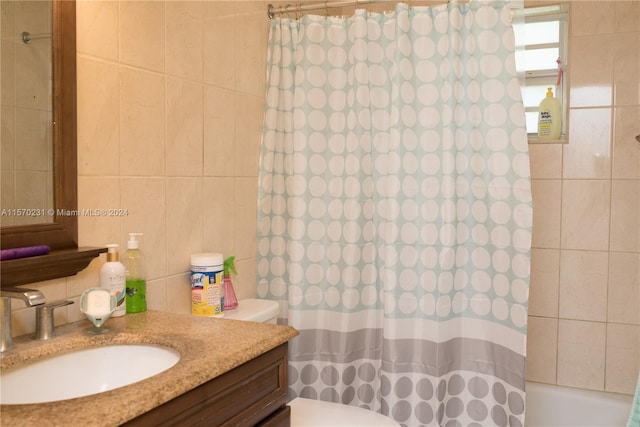 full bathroom with vanity, toilet, tile walls, and shower / tub combo