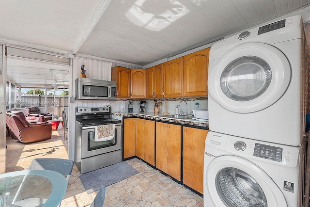 kitchen featuring stainless steel appliances, stacked washer and clothes dryer, backsplash, sink, and light tile flooring