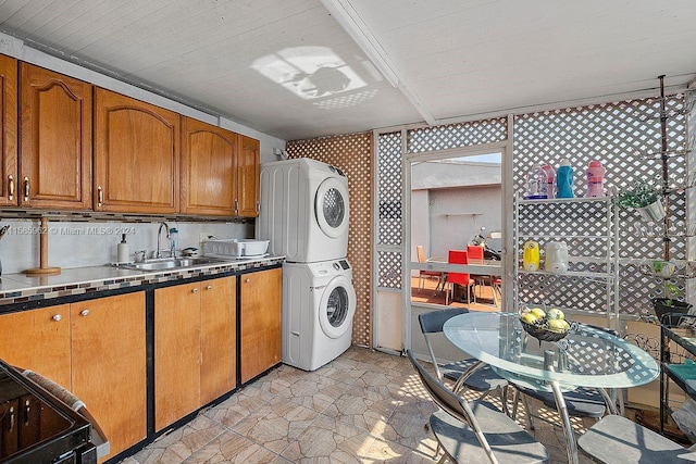 kitchen featuring stove, stacked washer / drying machine, backsplash, sink, and light tile floors