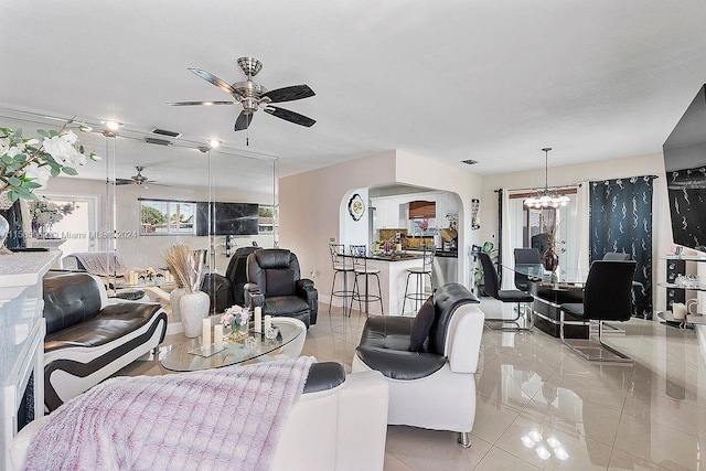 living room with ceiling fan with notable chandelier and light tile floors