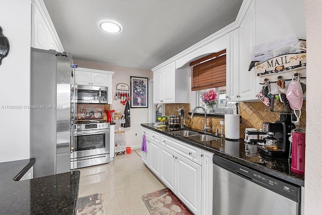 kitchen with appliances with stainless steel finishes, white cabinets, dark stone counters, sink, and tasteful backsplash